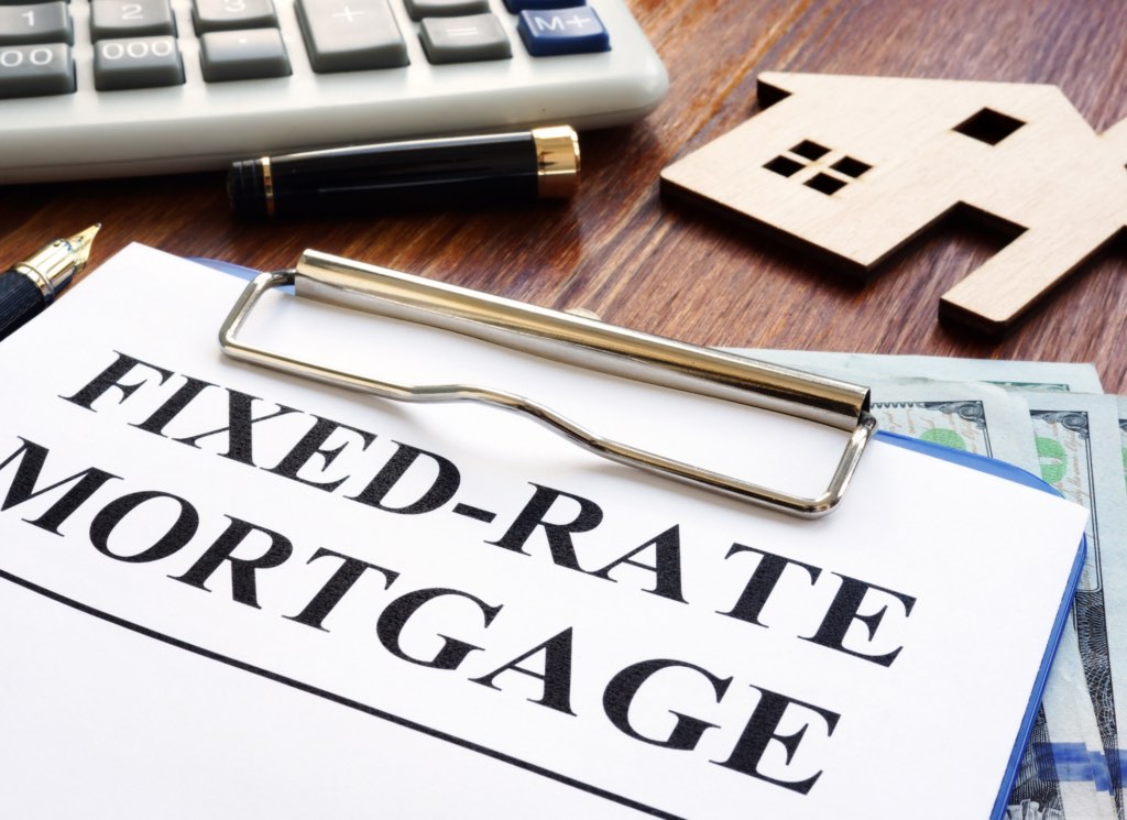 A Minnesota homebuyer reviewing fixed-rate and adjustable-rate mortgage options with a calculator and loan documents on a table.