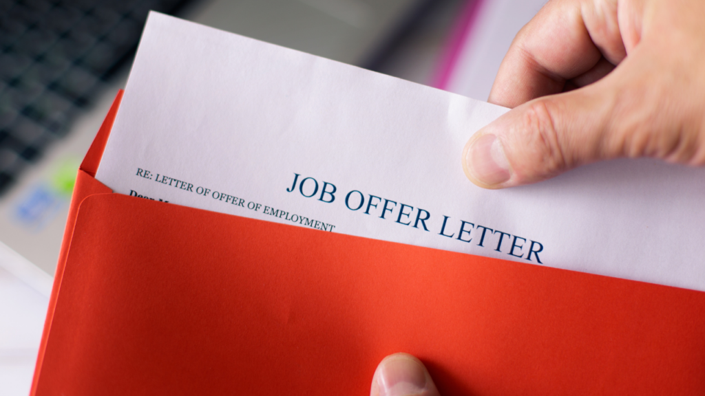 Immigrant professional in Minnesota reviewing a job offer letter with a mortgage lender to qualify for a home loan before starting their new position in the Twin Cities