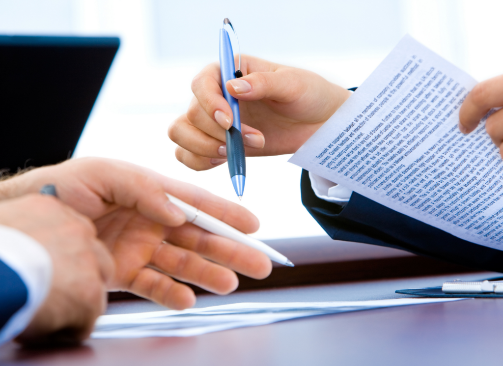 A real estate agent and clients reviewing a purchase agreement and counteroffer paperwork at a table in Minnesota.