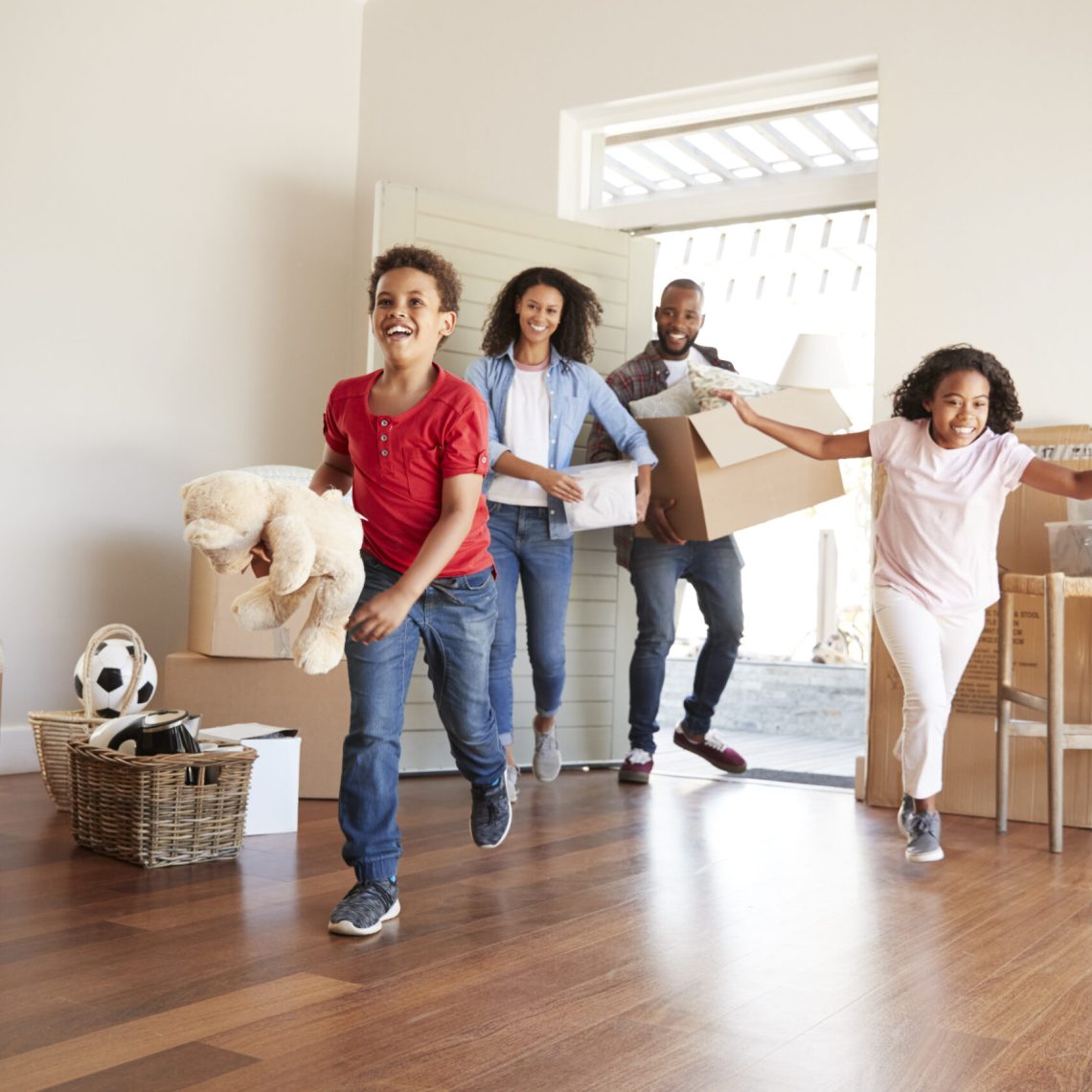 Excited Family Carrying Boxes Into New Home On Moving Day